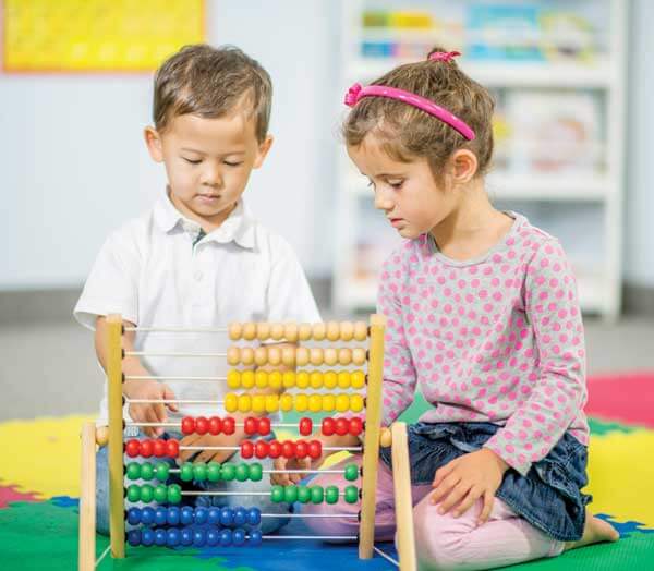 Two young children playing attentively with a multicolor wooden bead roller coaster