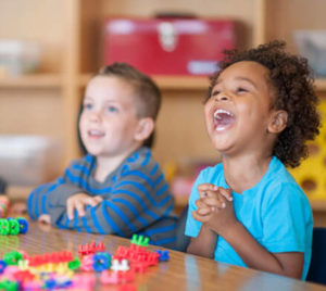 Two young children sitting at a table with nice smiles